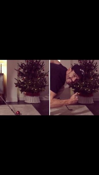 Man decorates christmas tree with golf club